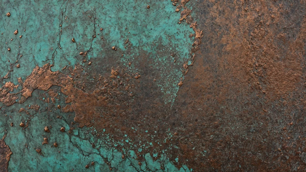 A sheet of weathered copper photographed close, turquoise and green patina spreading in irregular blooms across the warm brown metal.