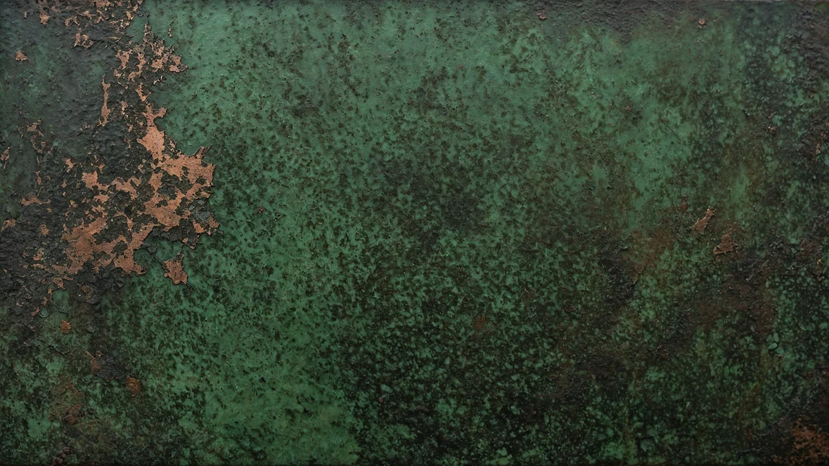 A field of deep green copper patina photographed close, flecks of bare warm metal showing through where the surface has worn away.